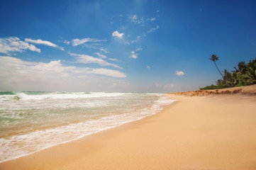 beautiful landscape with sandy ocean beach in waves, blue cloudy sky