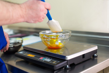 Man weighs caramel in a glass bowl on electronic balance