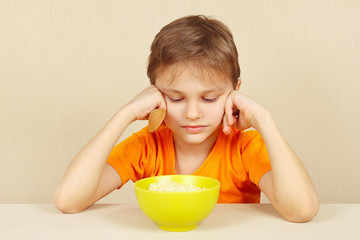Little unhappy boy does not want to eat a porridge