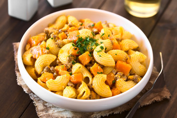 Hörnchennudeln mit Hackfleisch- und Kürbissauce bestreut mit Petersilie, fotografiert mit natürlichem Licht (Selektiver Fokus, Fokus in die Mitte des Gerichts)