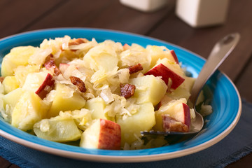 Salat aus Sauerkraut, Apfel, Kartoffeln und Speck, fotografiert mit natürlichem Licht (Selektiver Fokus, Fokus ein Drittel in den Salat)