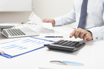 Man using calculator and holding important document