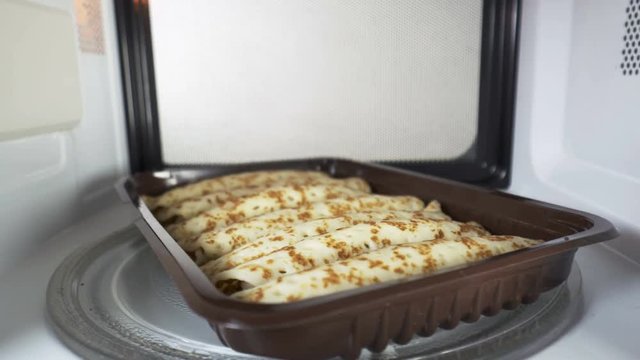 Frozen pancake rolls heating in microwave oven inside view