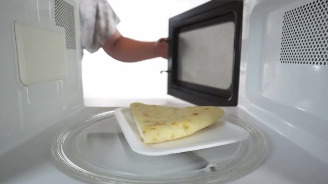 Reheating leftover slice of cheese pie on supermarket styrofoam tray in the microwave oven