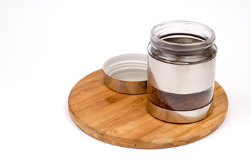 Glass jar with grated coffee over white background