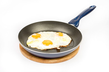 Fried eggs in teflon frying pan over white background