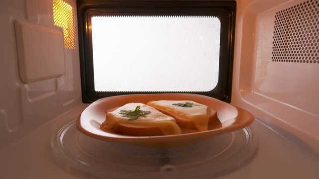 Making toasts with melted cheese in the microwave oven inside view. Version without external lighting for more natural look.
