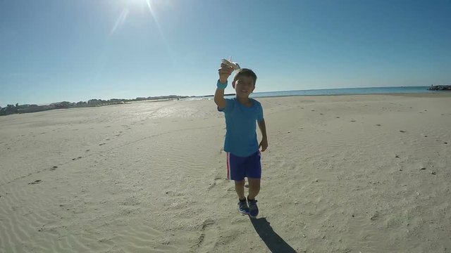 Boy with model airplane running on sand