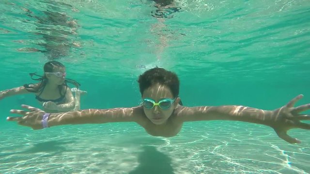girl and boy swimming under water