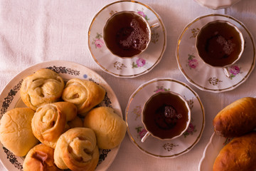 
delicious hot homemade cakes and a cup of tea on a white tablecloth at home at the table