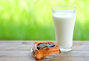 Blue berry pie  with milk glass on wooden table,green blurred ba