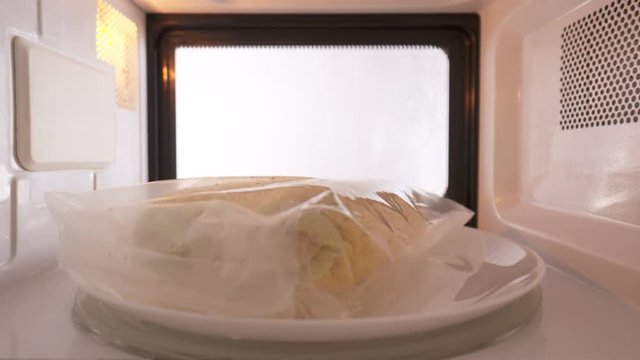 Ears of corn in plastic bag in microwave spinning on tray