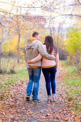 Fototapeta premium smiling couple hugging in autumn park from back