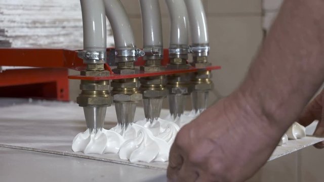 Confectionery factory production of sweet marshmallow zephyr. Close up of small marshmallow making machine nozzles.
