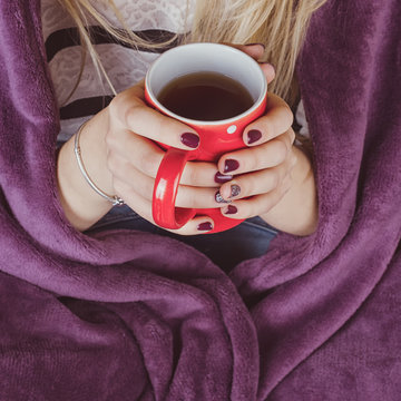 female hands holding mug of hot tea