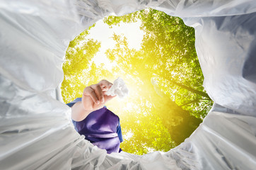 Man holding used tissue for recycling, viewed from inside recycling bin. Copy space