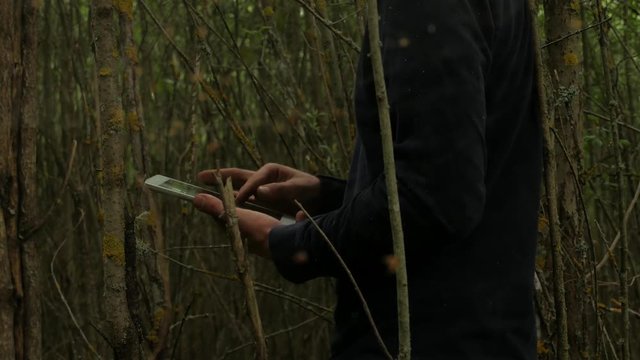 Man use tablet computer in  a deep forest.  Focusing through the cobwebs