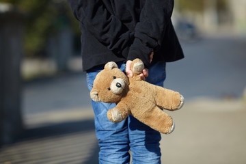 little homeless boy holding a teddy bear