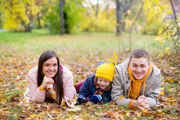 Fototapeta premium family lying on the leaves autumn park
