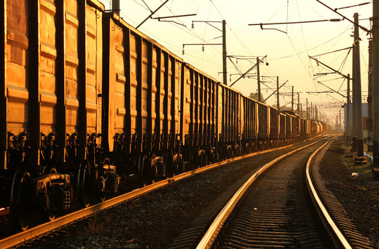 Fototapeta Freight train moving on the tracks at sunset
