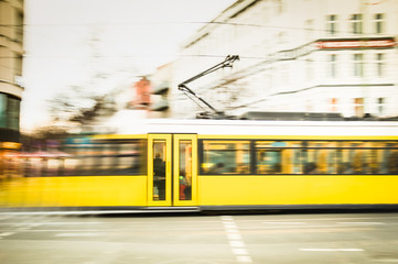 Blurred motion of defocused yellow tram on the streets of Berlin - Transport concept with public vehicle speeding at rush hour on city road - Warm vintage filter with blurry composition © Mirko Vitali