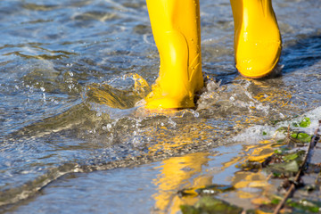 On a sunny day with rubber boots running through water
