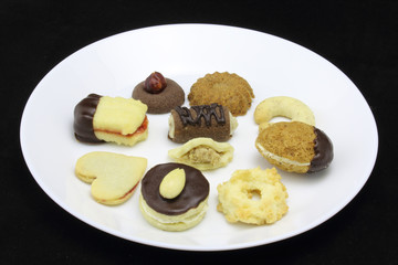 Variation of homemade Christmas cookies, special Czech sweets on white plate, isolated on black. Pastry, cookies, biscuit, cracker with spice (vanilla, cinnamon) and nuts (walnuts) like tea biscuits
