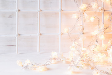 Christmas soft home decor with lights burning  on a white wooden background. Xmas background.