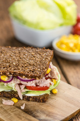 Wooden table with Tuna sandwich (on wholemeal bread; selective f