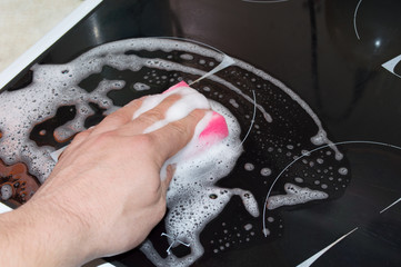 Hand cleaning cooker at home kitchen closeup