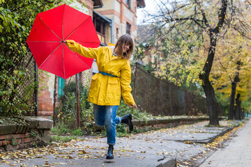 Enjoying autumn days. Woman in yellow raincoat walking down the street