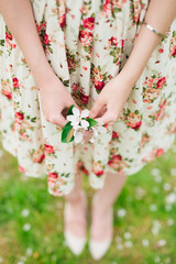 Obraz na płótnie Canvas girl in flower dress holding sakura cherry blossom in hands