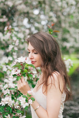 Naklejka premium Girl sniffing cherry flowers tree in park