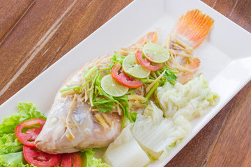 Steamed fish with chili and lemon on wood table , spicy food
