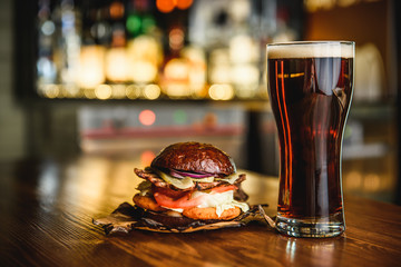 Hamburger and dark beer on a pub background.