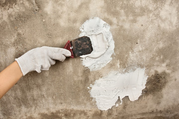hand with spatula plastering concrete wall