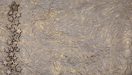 Silver paper background with wooden stars. Christmas theme