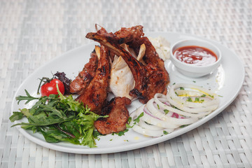 fried pork ribs with pita bread, sauce and onion rings on an oval plate