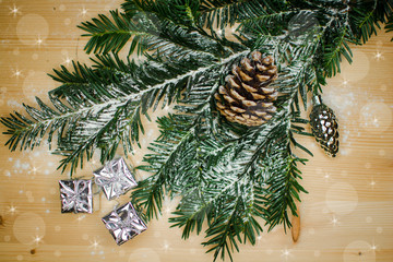 christmas branch winter decoration with stars, snow flakes ,snowman and little silver shiny presents and one big pinecone on wooden table