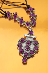 Silver fashion jewelry with purple rhinestones on orange mirror background 