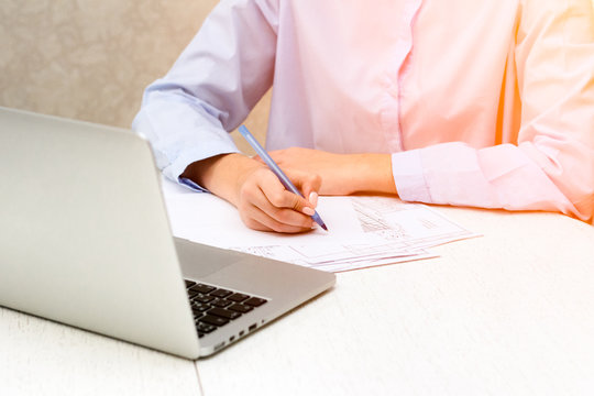 Hand, laptop at home at the table, she writes pen on paper