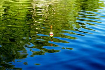 A fishing float on the water surface of the lake while fishing © toshket