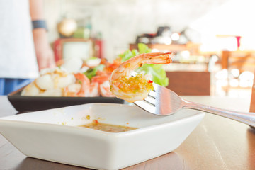 grilled shrimp on a fork with sea food sauce on wood table, Thai food