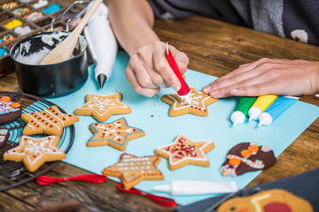 woman decorating gingerbread Christmas cookies