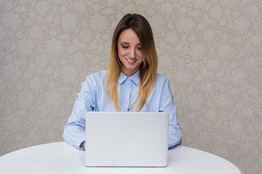 Young beautiful girl with a laptop at home at the table, smile,fun