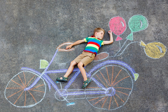 little kid boy having fun with bicycle chalks picture on ground