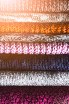 Stack of colors cozy knitted sweaters and sunlight