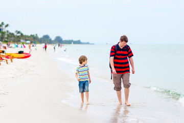 Little kid boy and father having fun with collecting shells