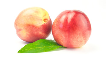 Ripe juicy nectarines with green leaves isolated on white background