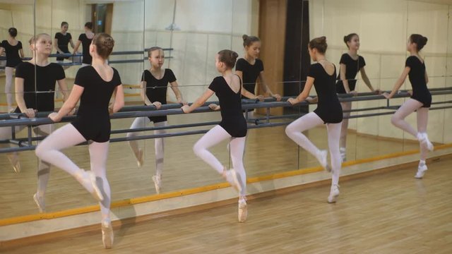 group of four young ballerinas standing in row and practicing ballet